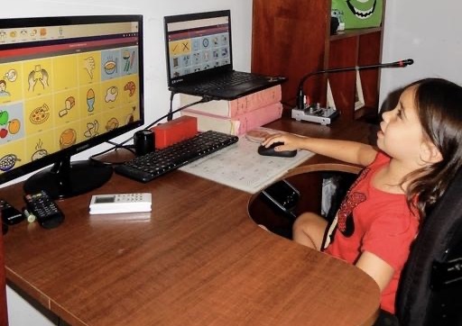 A young girl using a computer with the AAC tool Cboard