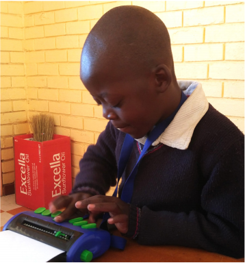 An early grade student learning how to use a Braille device in Lesotho
